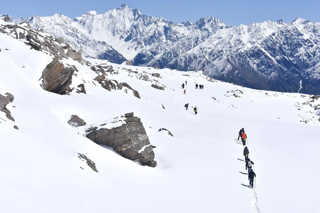 A group of trekkers traverse a snow covered trail on Buran Ghati Trek.