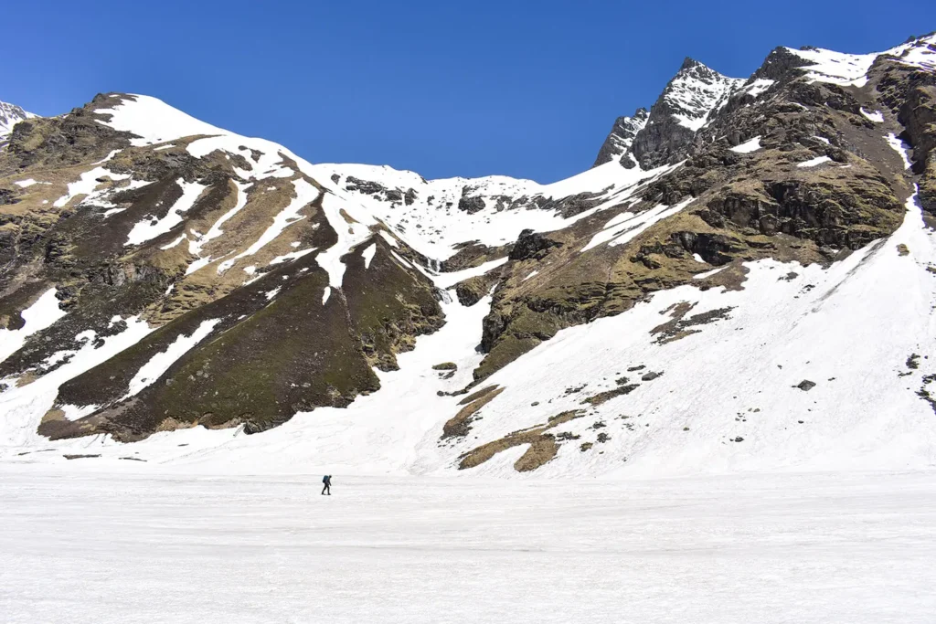 A trekker traverse a vast snow covered trail on Buran Ghati Trek.