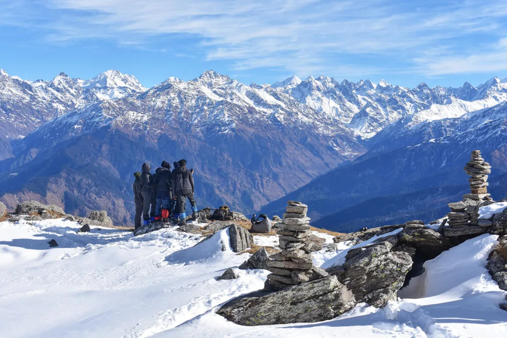 Reaching the pinnacle of their journey, OWLS trekkers stand on the snow-capped peak of Kedarkantha